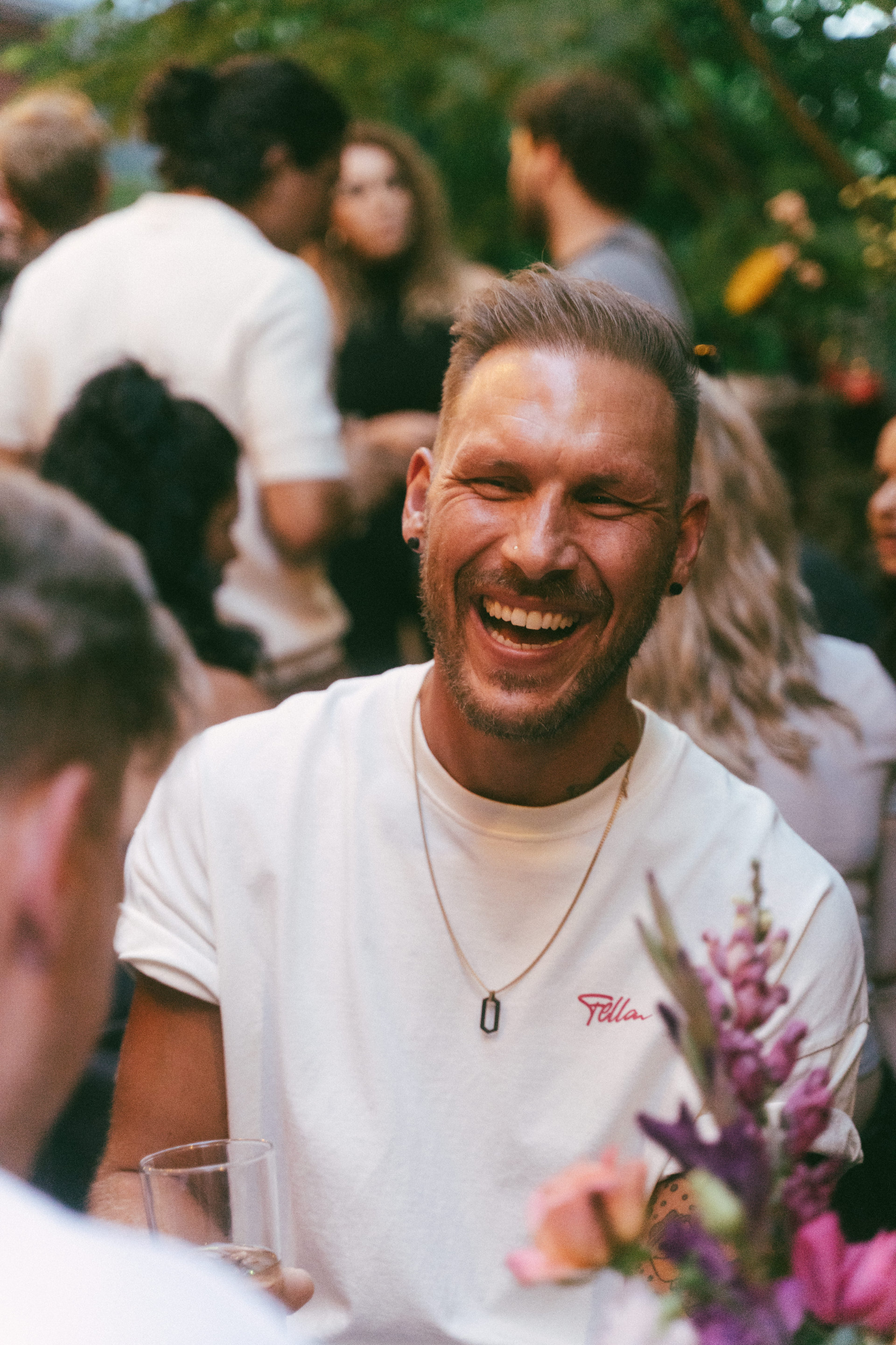 A guy with a beaming smile enjoying a lively outdoor social gathering.