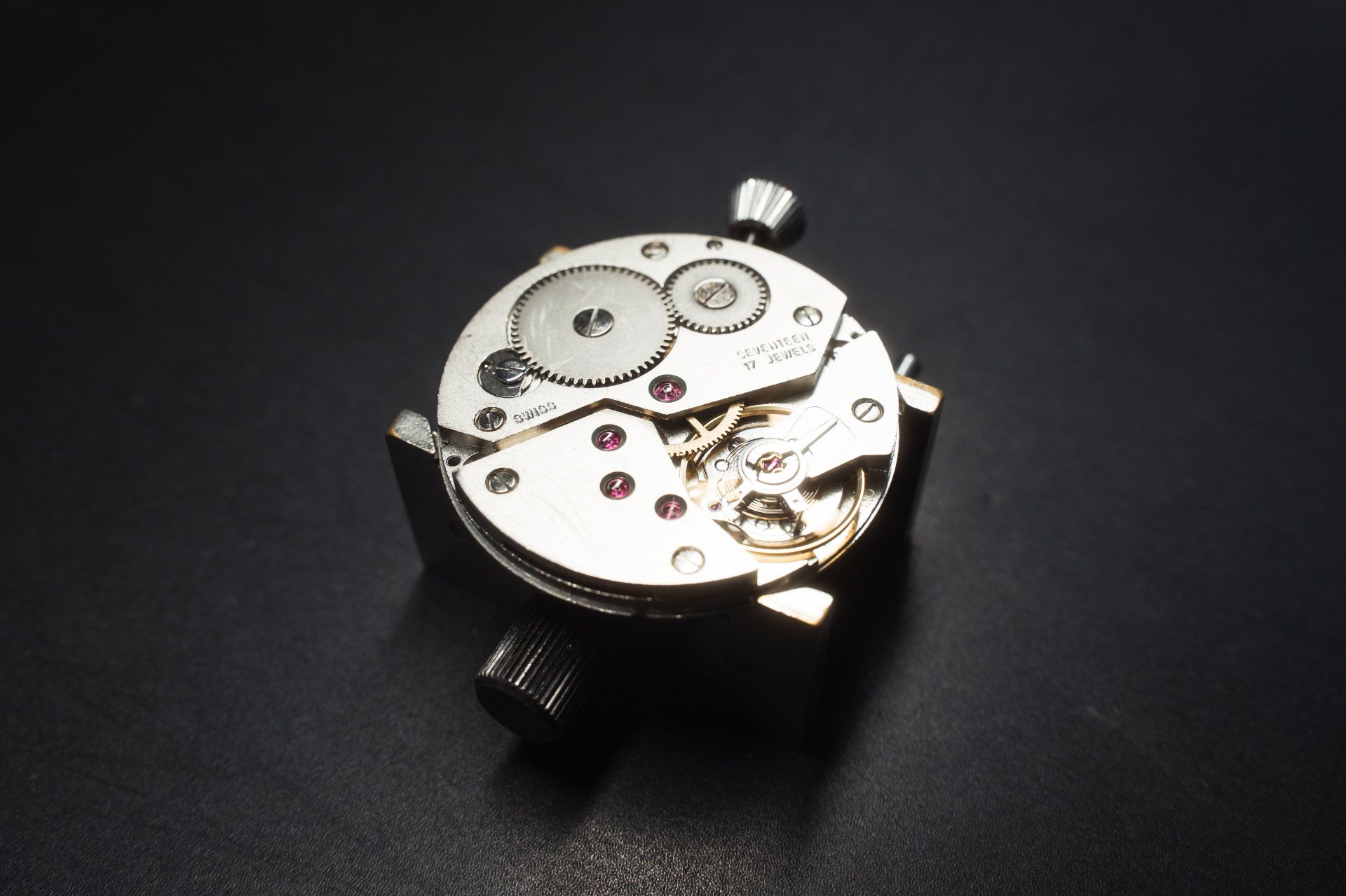 Intricate watch movement on a dark surface, showcasing the precision engineering of horology.