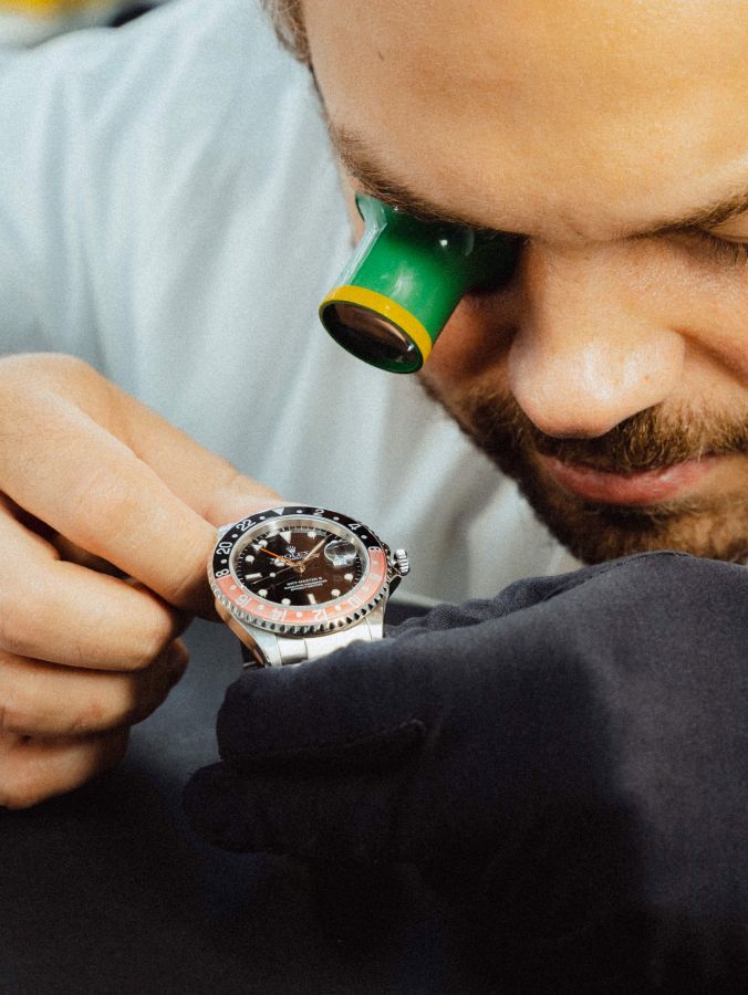 A watchmaker meticulously inspects a luxury wristwatch with a jeweler's loupe, showcasing the precision and care that goes into the craft of horology.