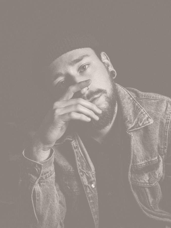 A contemplative man in a beanie and denim jacket, with a thoughtful expression, captured in monochrome tones.
