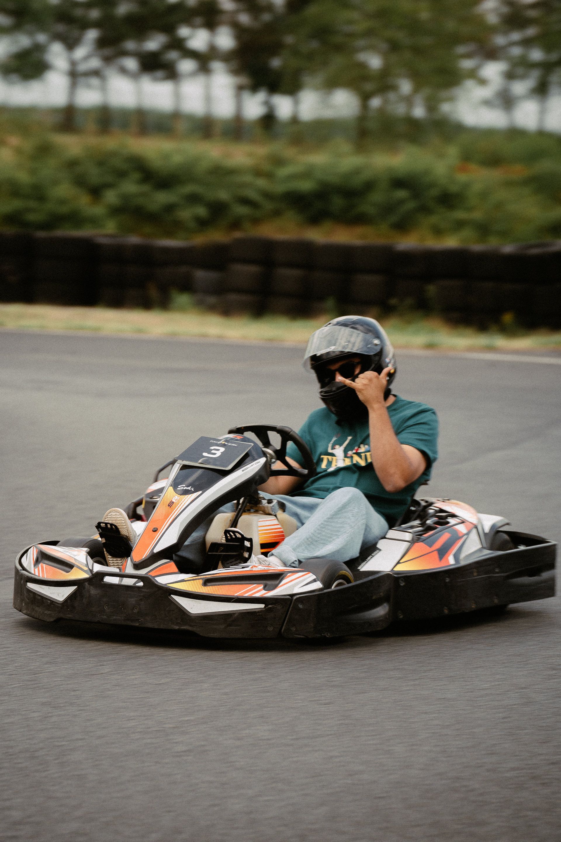 A person wearing a helmet is engaged in an exciting go-kart race, taking a sharp turn on an asphalt track, captured by an Aschaffenburg photographer.