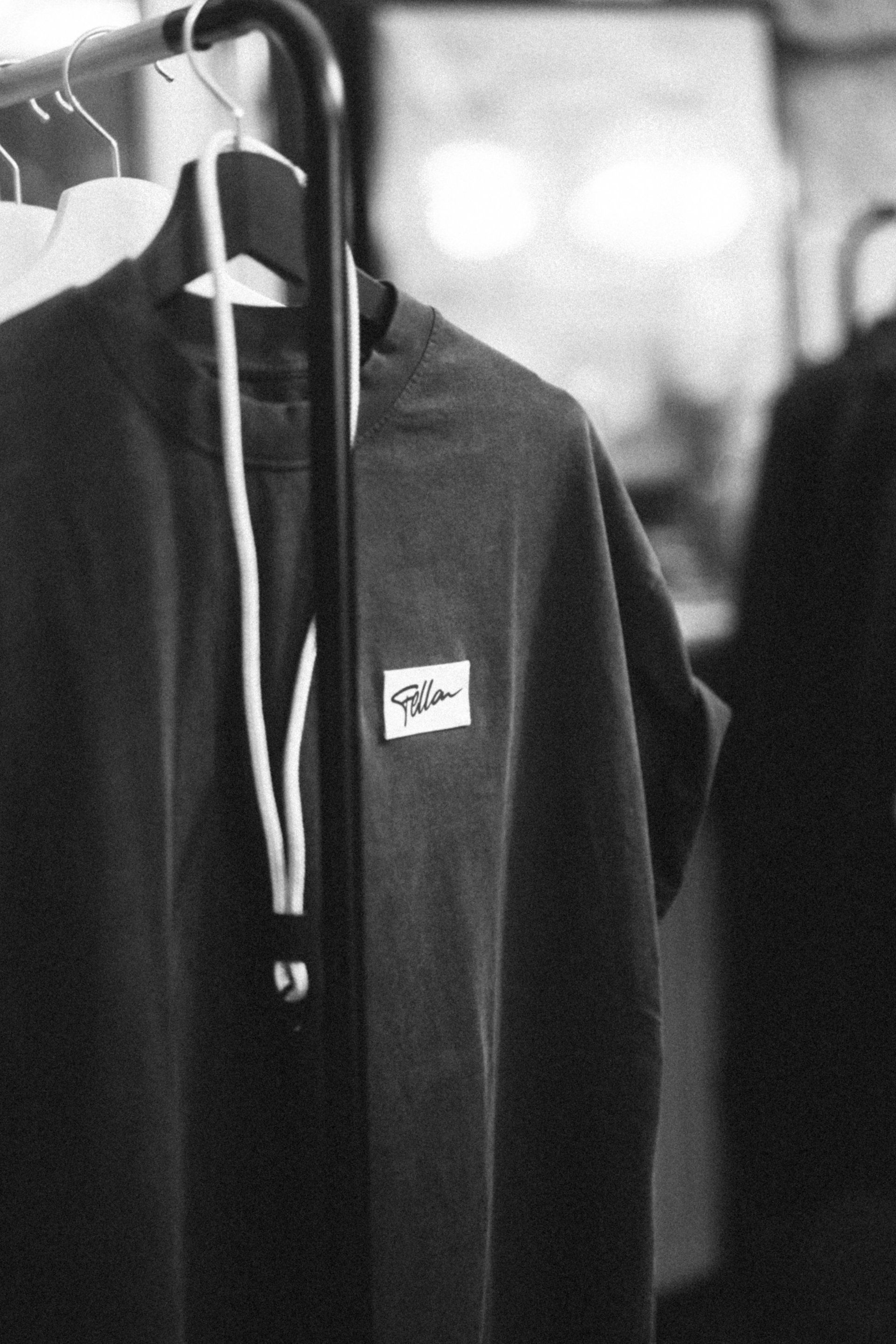 A monochromatic glimpse into a fashion-forward wardrobe featuring a shirt with a visible branded tag hanging amidst other apparel.
