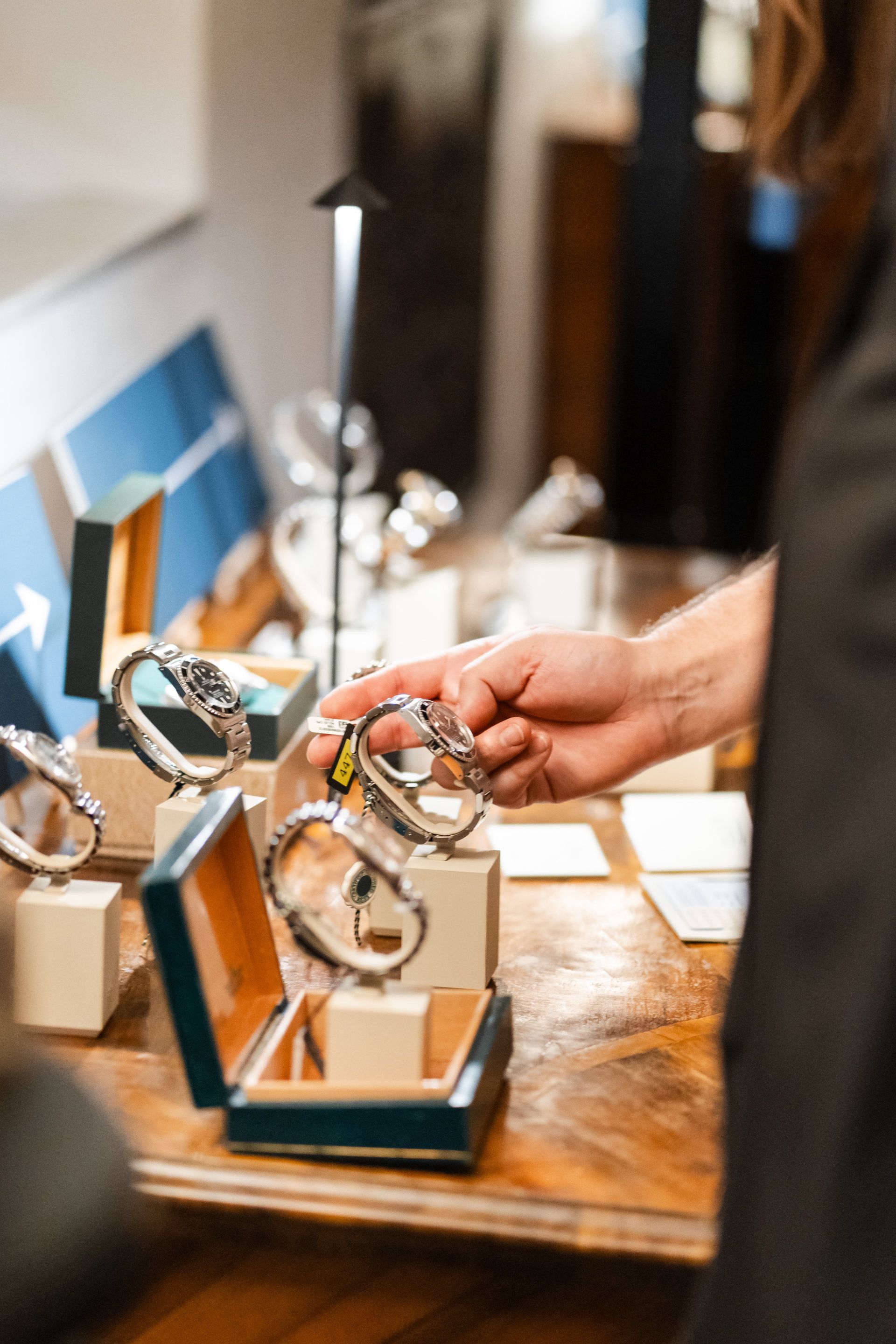 A person examines a luxury watch at a display counter, highlighting the careful consideration given to choosing a high-quality timepiece for an event showcase.