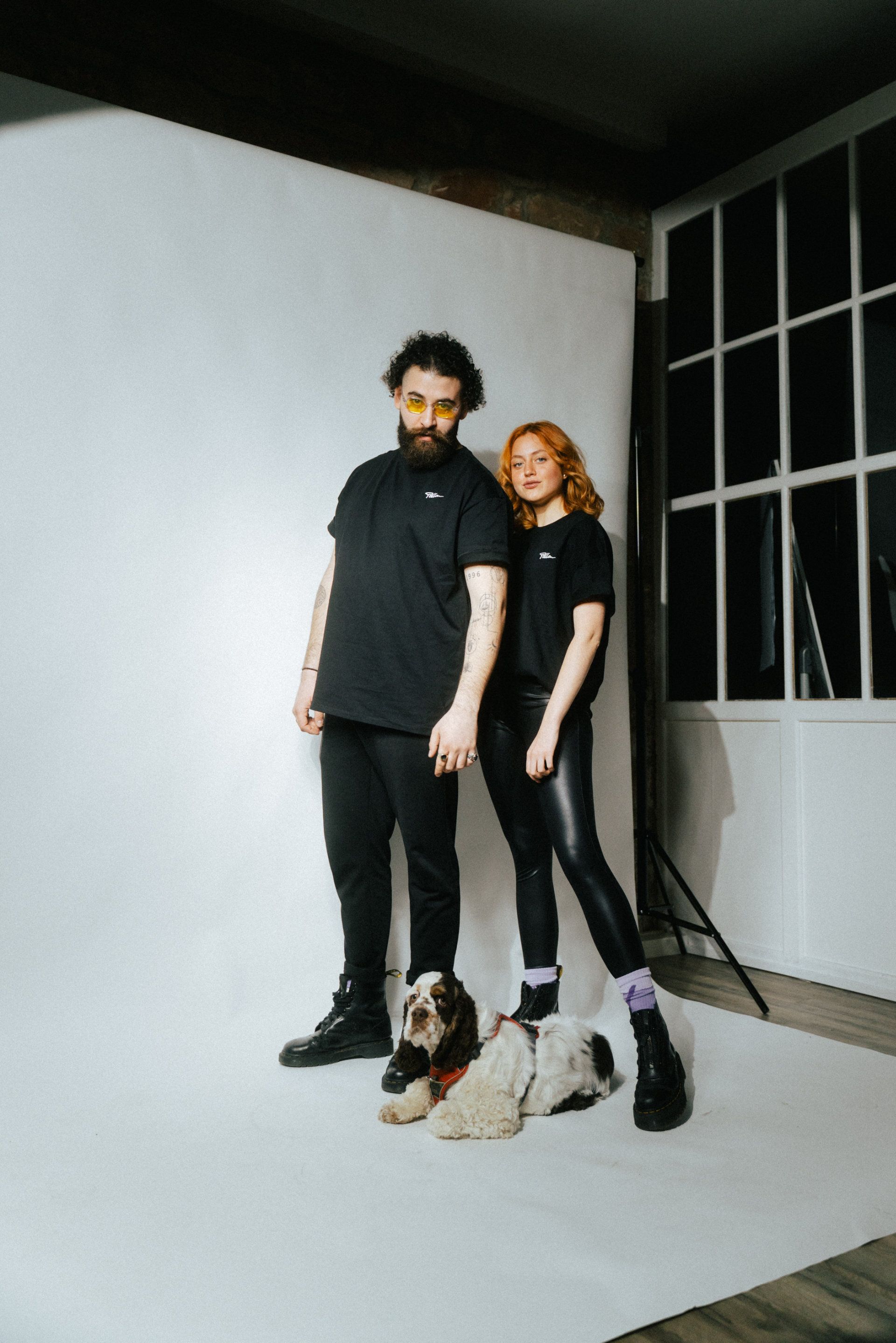 A stylish couple posing in a photo studio with a cute dog at their feet, taken by a photographer from Aschaffenburg.