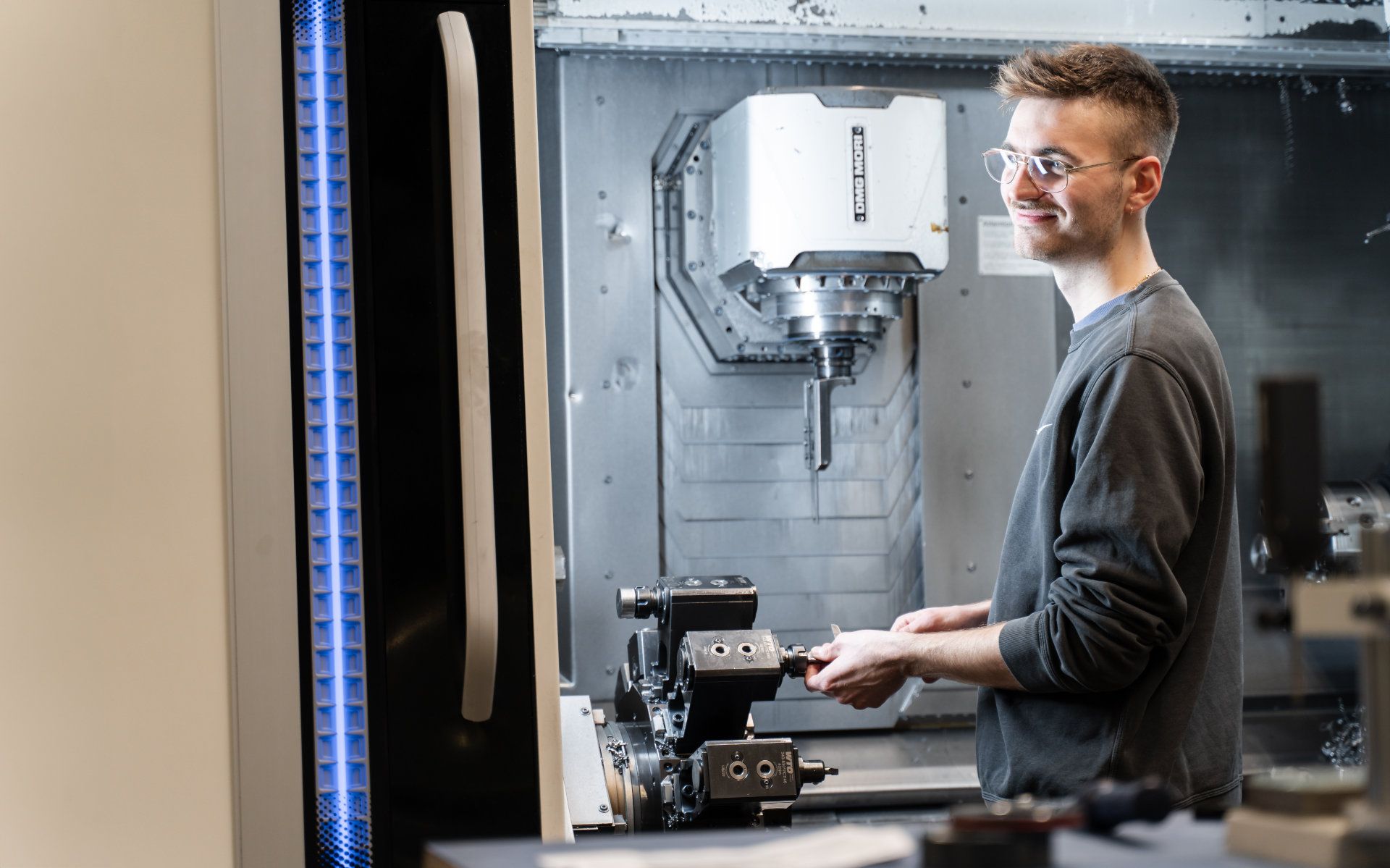 A smiling technician operating precision machinery in a modern industrial environment.